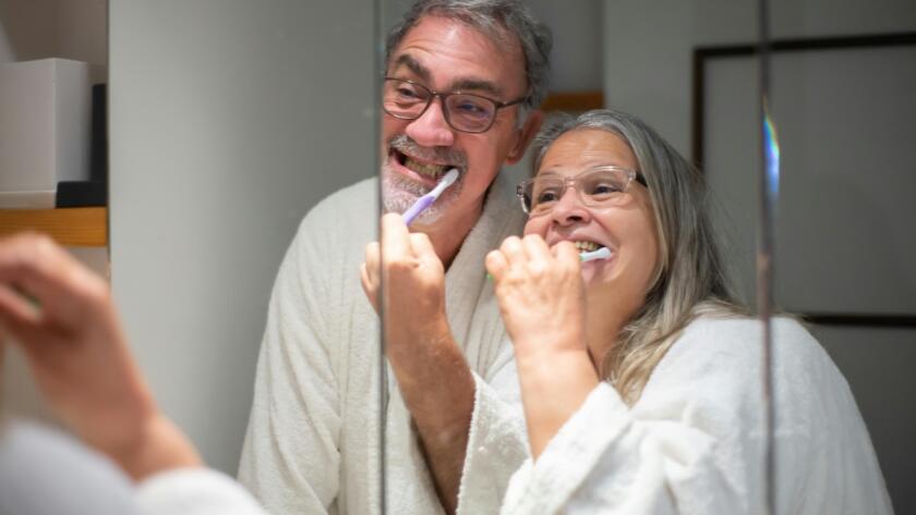 Older couple brushing their teeth at home as part of daily oral care