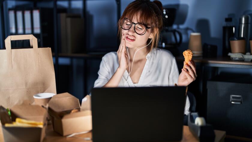 Woman holding her jaw in pain at night while eating, illustrating tooth pain that worsens when lying down
