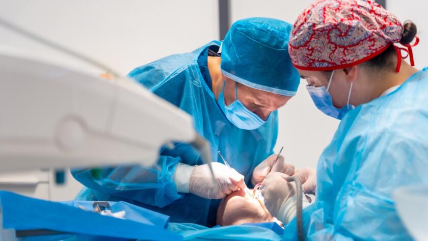 A dentist and assistant performing dental implant surgery